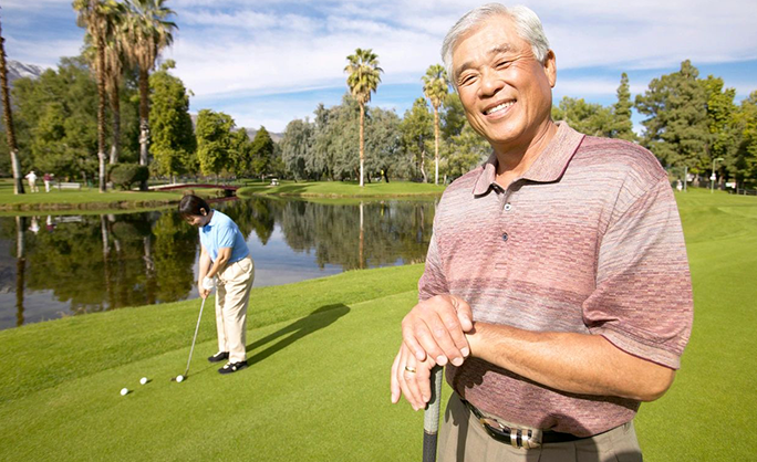 A man standing on top of a golf course holding onto his club.